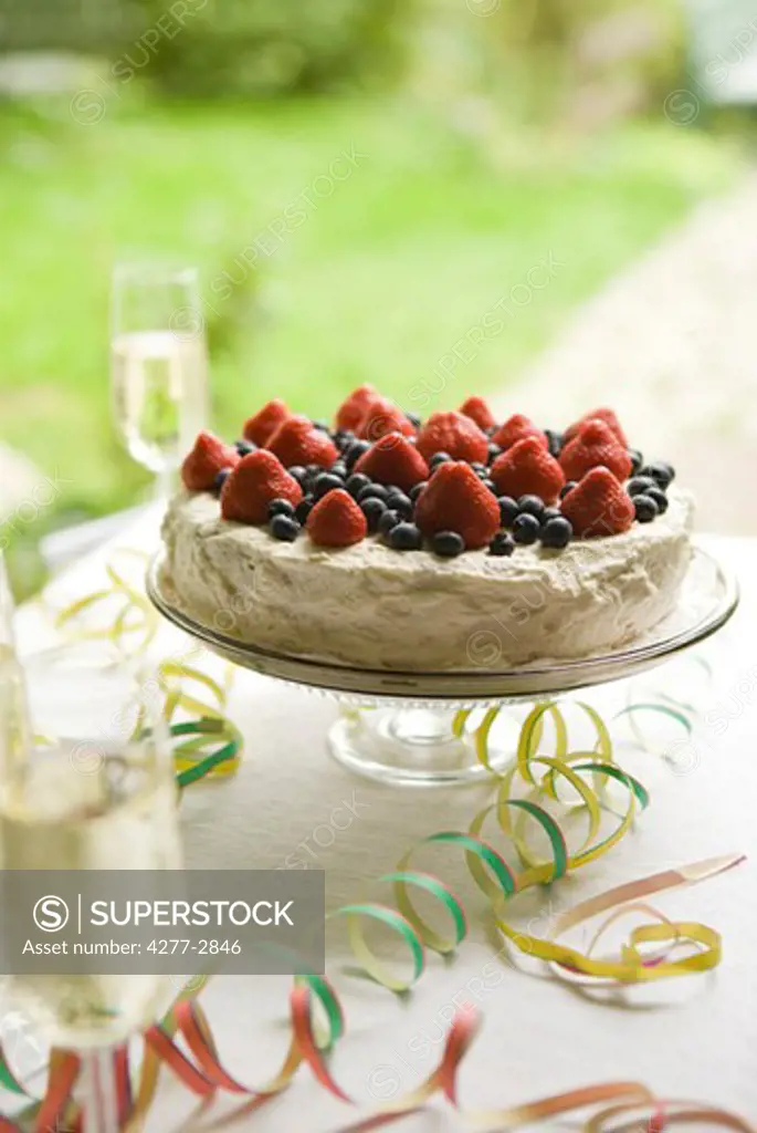 Strawberry blueberry cake on table decorated with party streamers