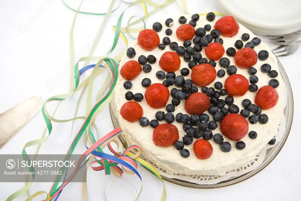 Strawberry blueberry cake surrounded by party streamers
