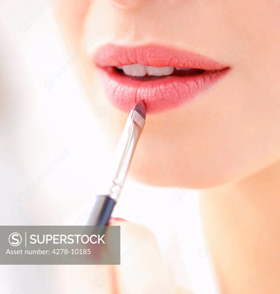Woman Applying Lipstick with Makeup Brush, Close-up View