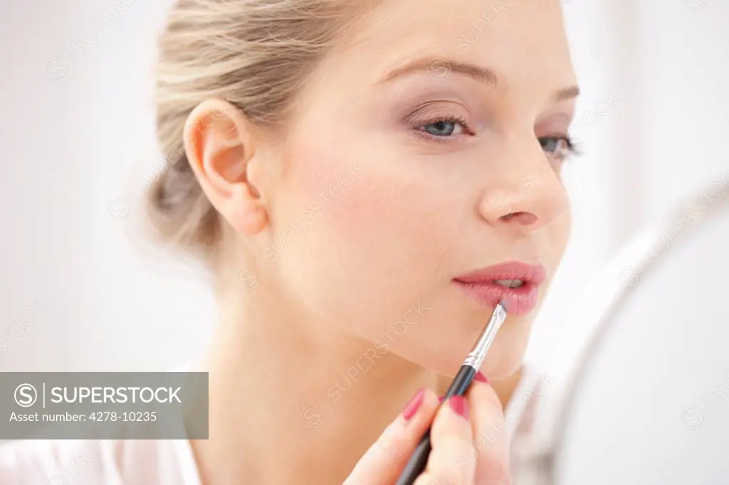 Woman Applying Lipstick with Makeup Brush