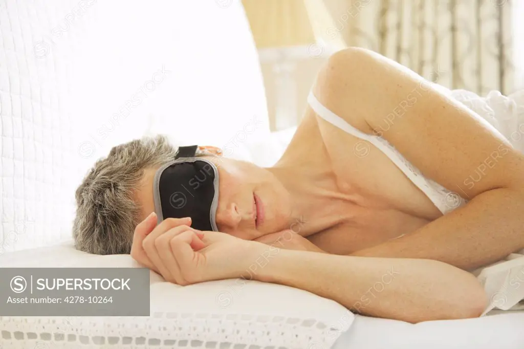 Woman In Bed Wearing Sleep Mask