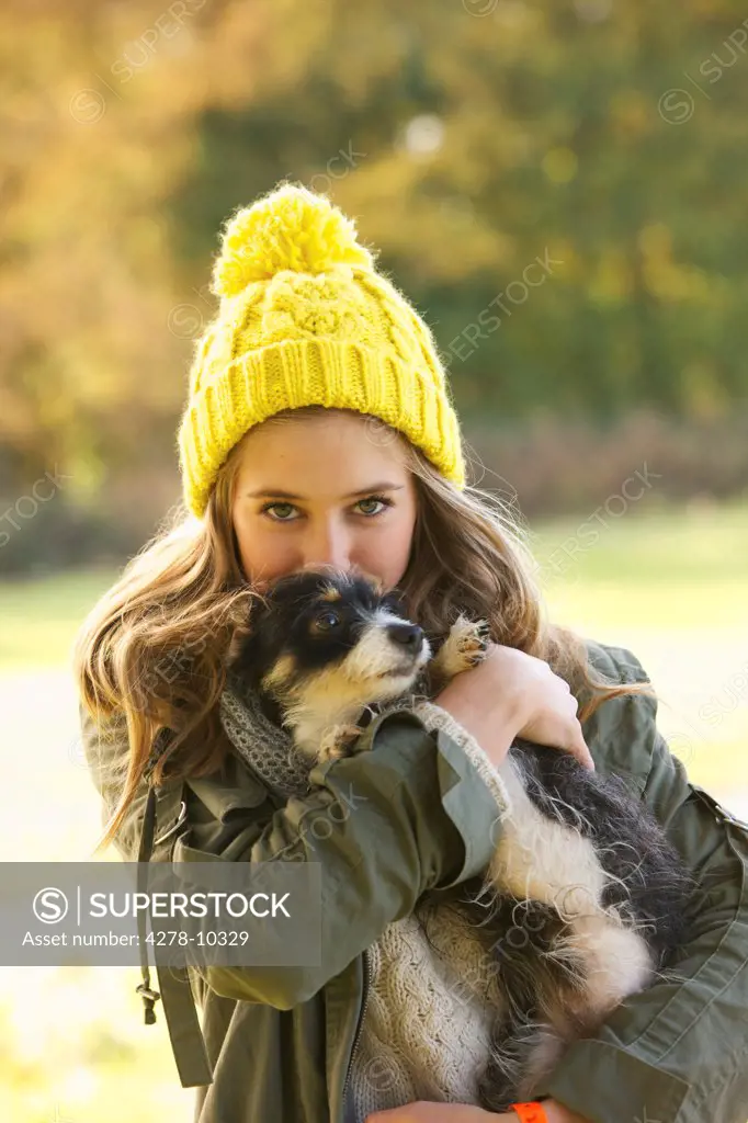 Teenage Girl Hugging Puppy Outdoors