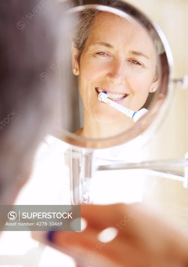 Woman Looking into Round Mirror Brushing Teeth
