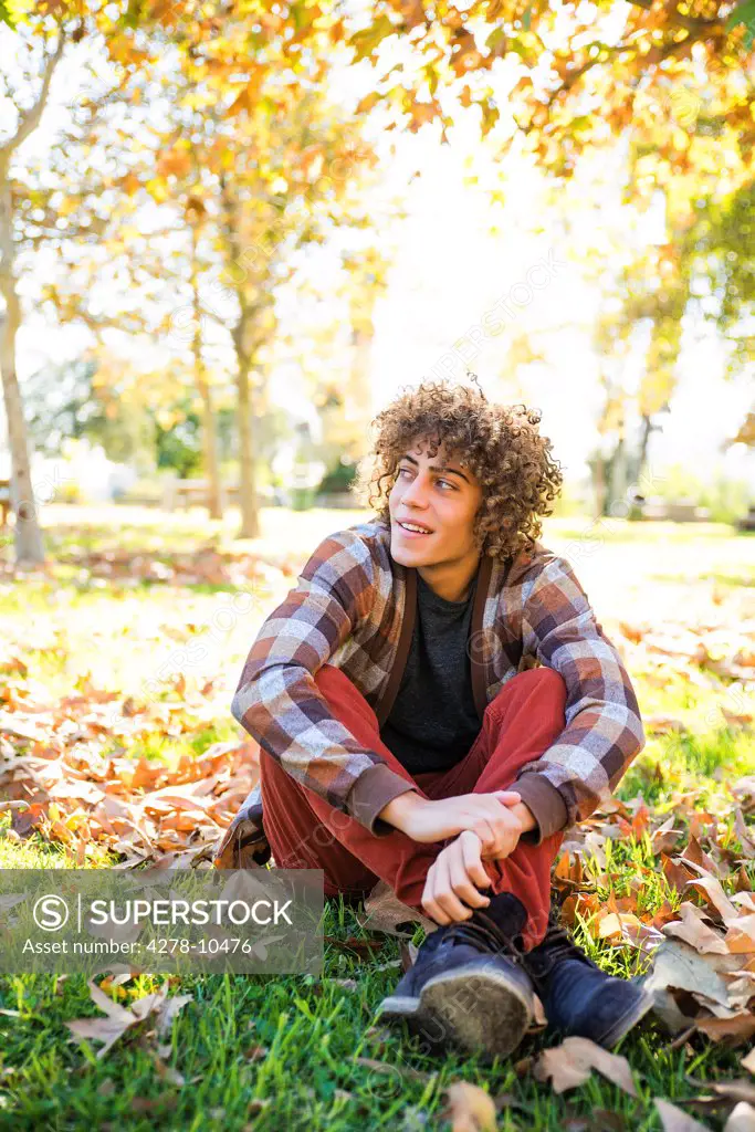 Young Man Sitting in Park in Autumn