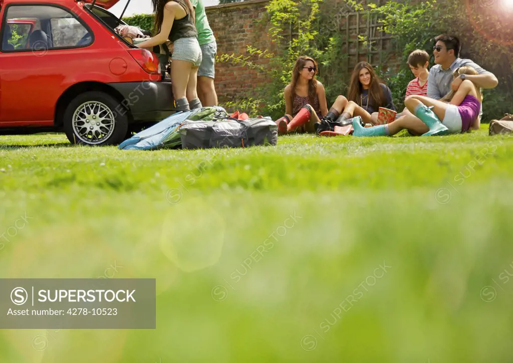 Teenagers Sitting on Grass and Loading up Car