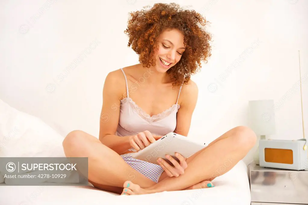 Woman Sitting on Bed Using Digital Tablet