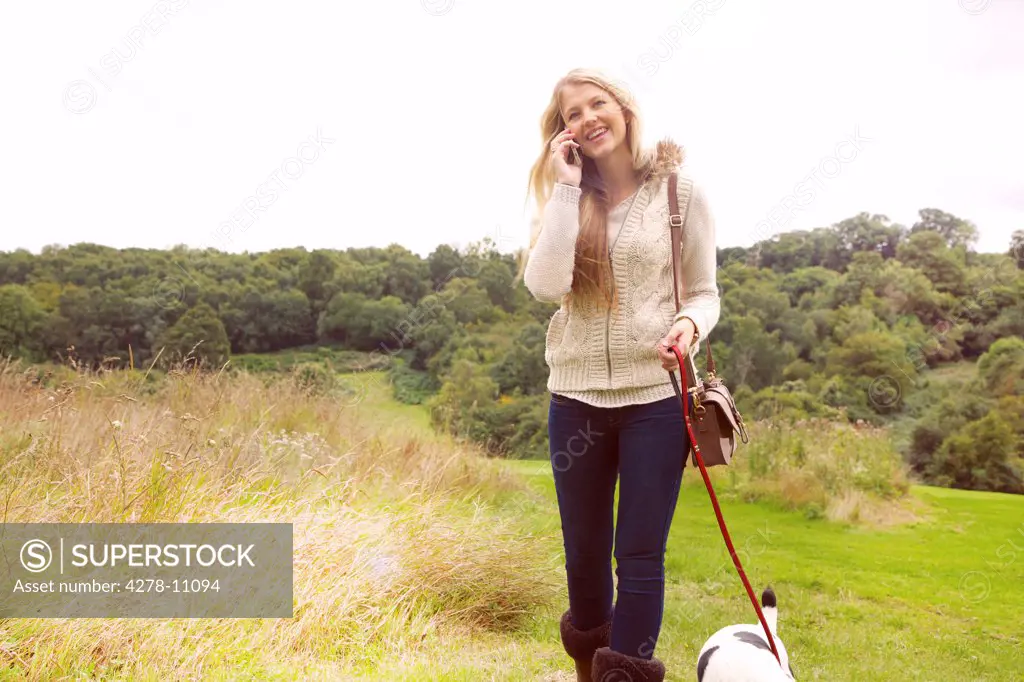 Young Woman Walking Dog and Using Phone