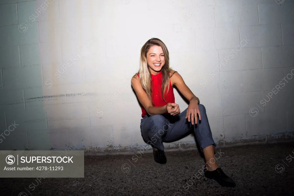 Smiling Woman Crouching against Wall
