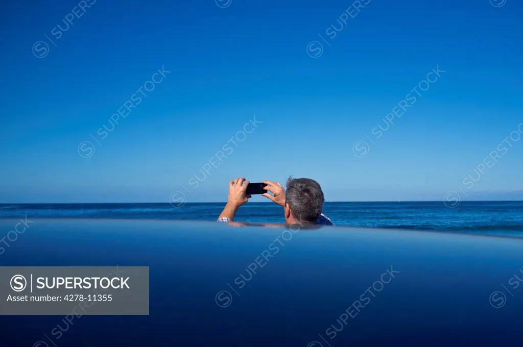 Back View of Man Taking a Photograph of Ocean View