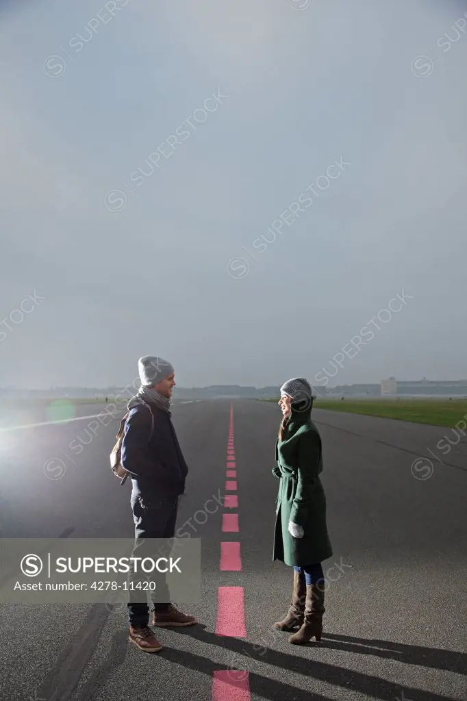Couple Standing on Airport Runway Facing each other
