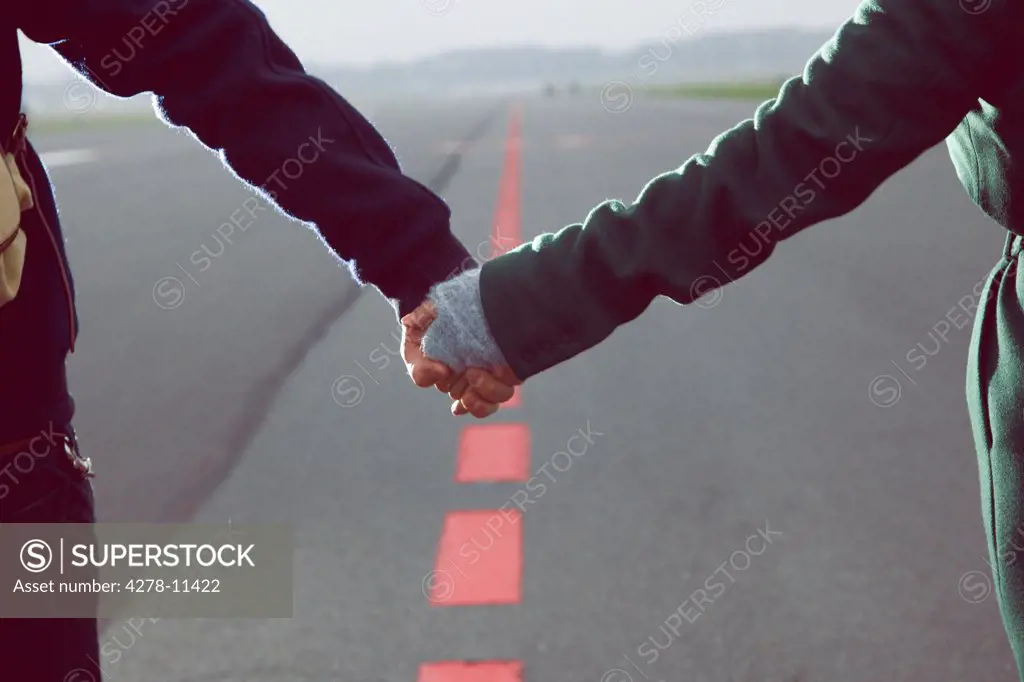 Couple Holding Hands on Airport Runway, Close-up view