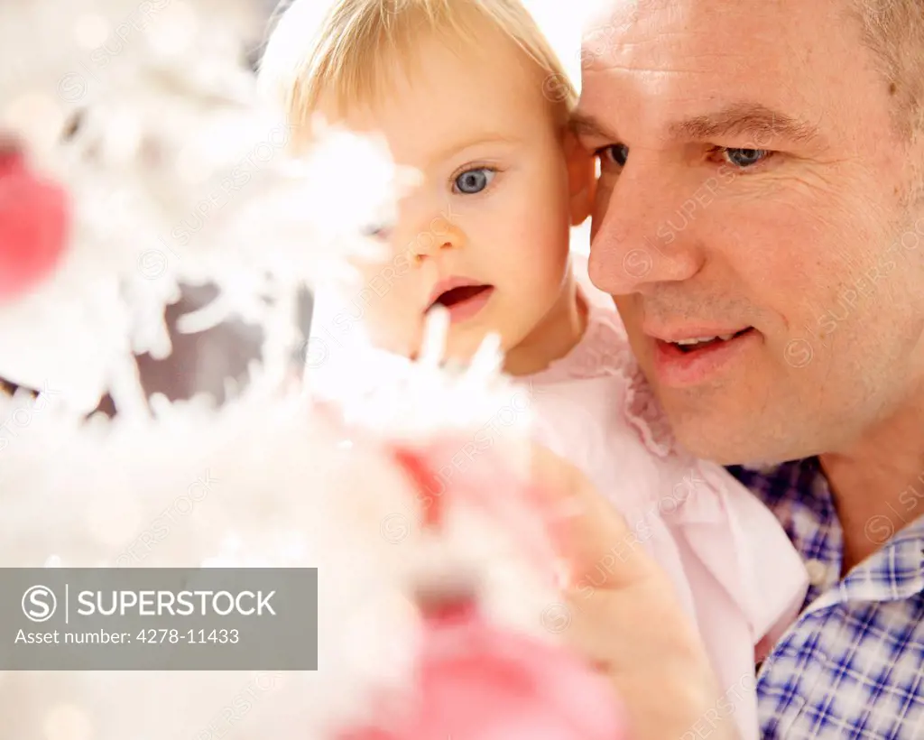 Father and Baby Daughter Looking at Christmas Tree, Close-up view