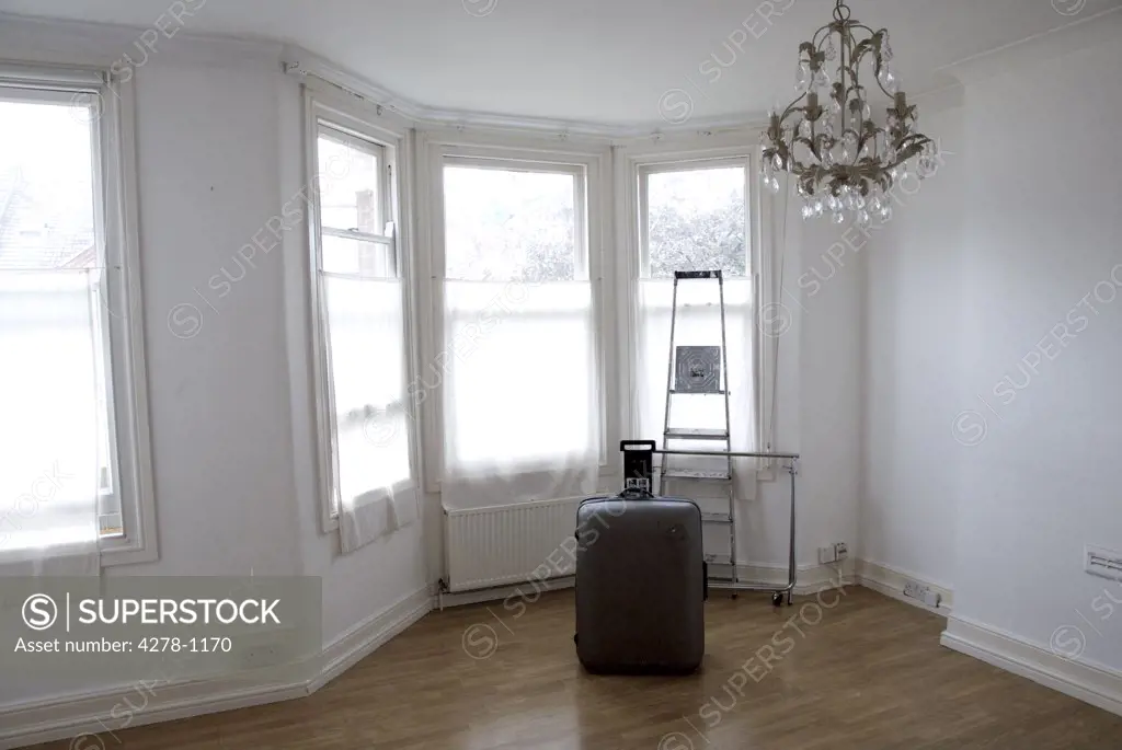 Empty room with suitcase and ladder