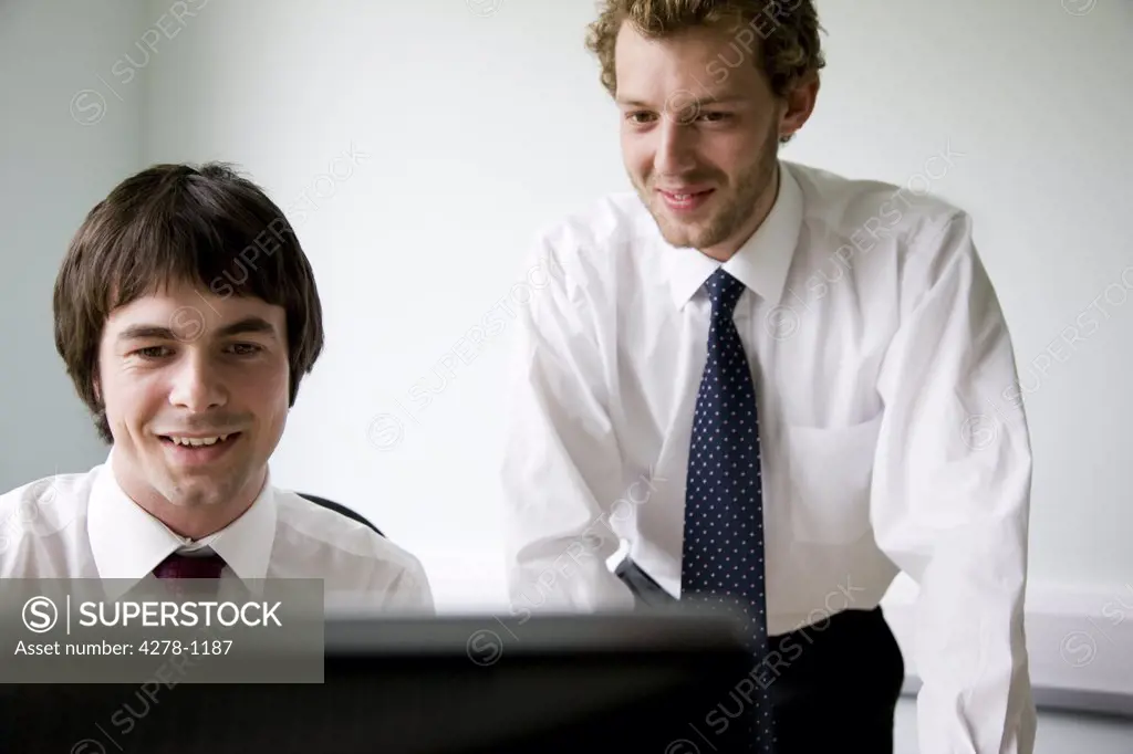 Close up of two young businessmen looking at computer monitor