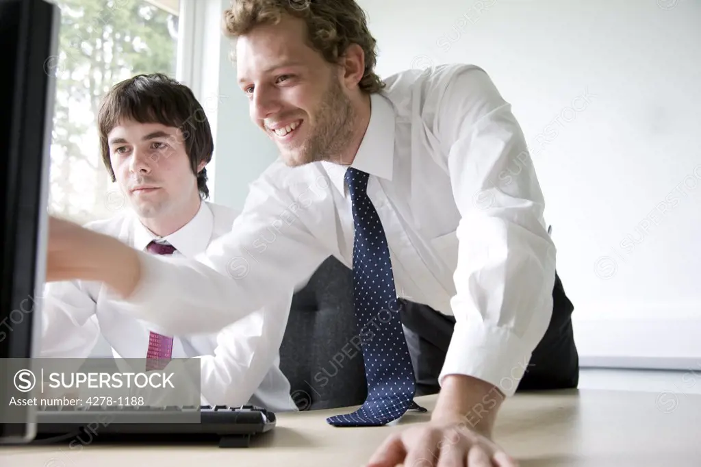 Young businessman pointing at computer monitor and touching screen with hand