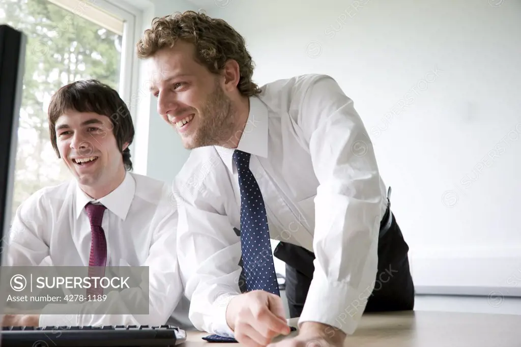 Young businessmen looking at computer monitor laughing