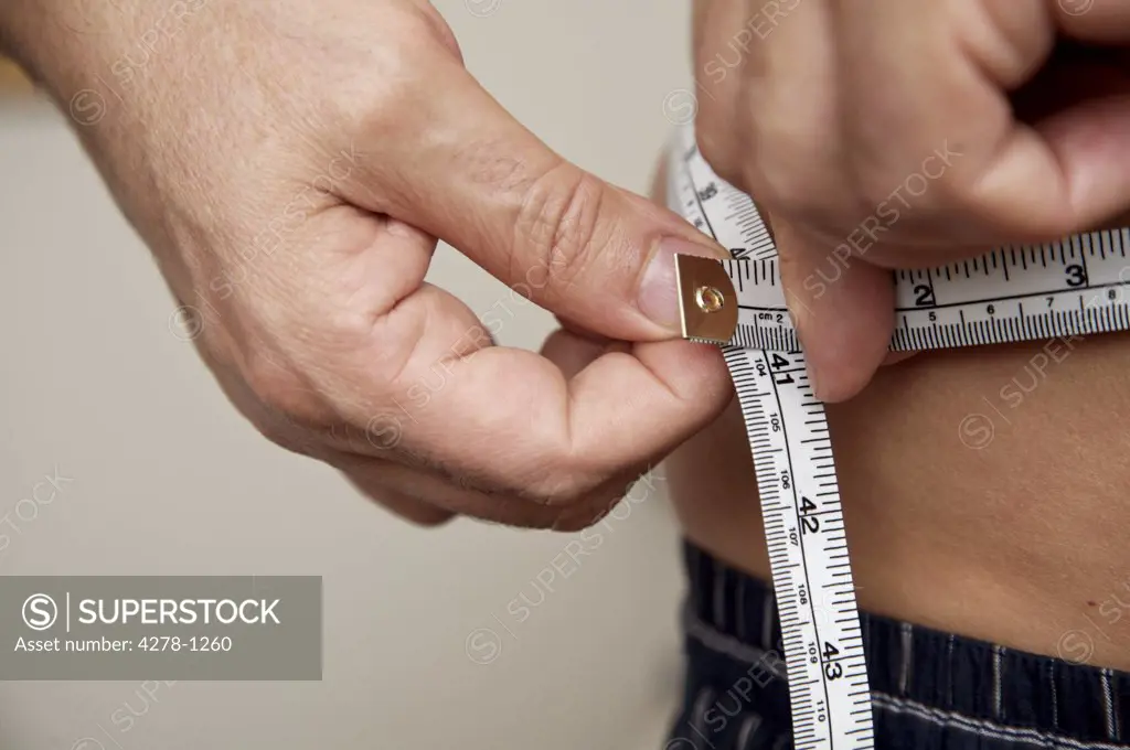 Close up of man measuring waist with tape measure