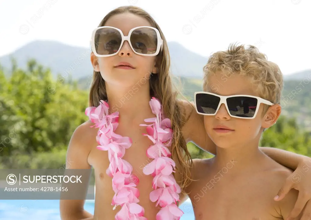 Young boy and young girl wearing oversized sunglasses