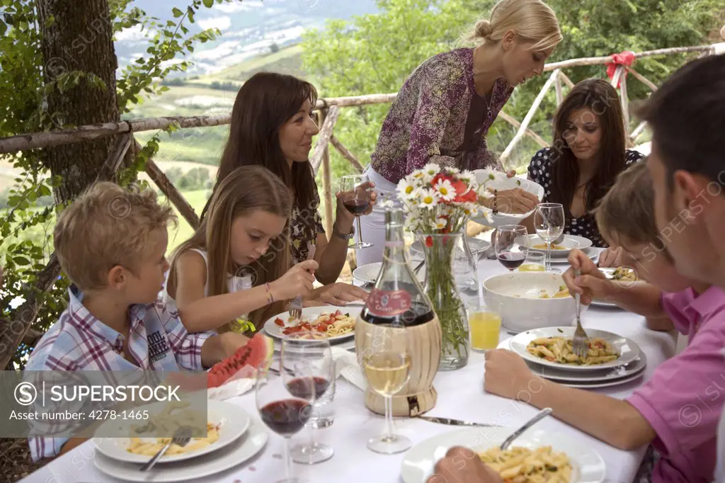 Extended family sitting at table having pasta meal