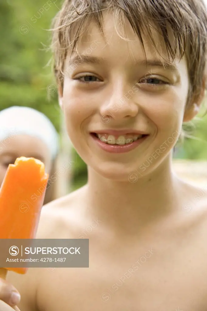 Young Boy eating orange ice-lolly