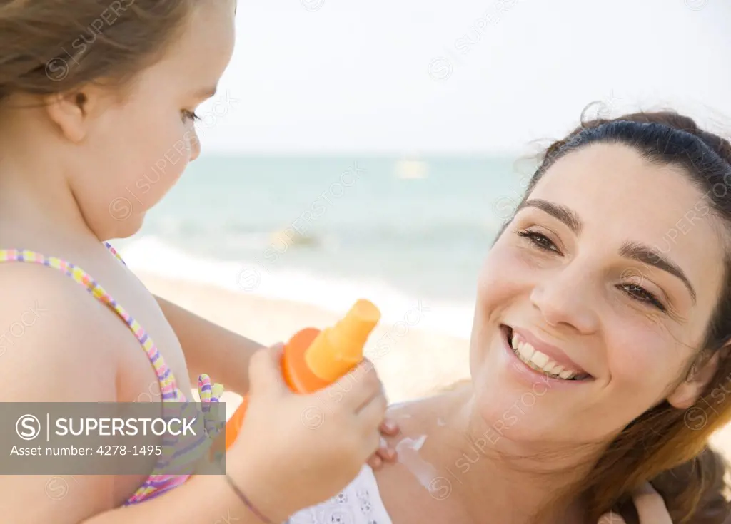 Daughter applying suntan lotion on mother's neck