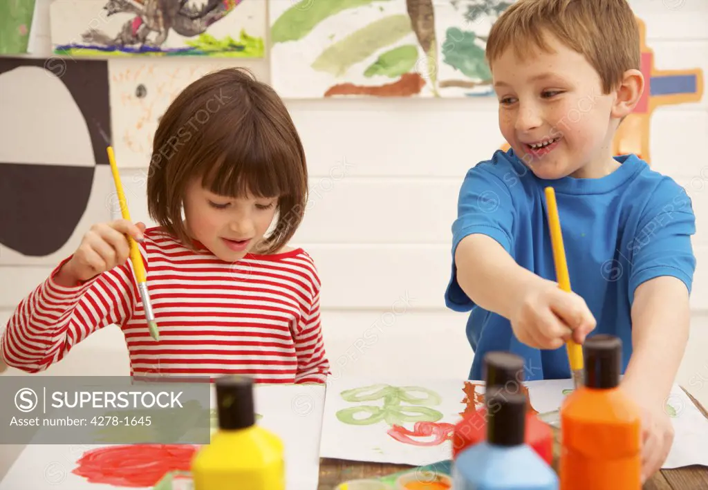 Portrait of a boy and young girl painting and smiling