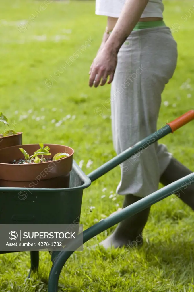 Young woman  standing next to wheelbarrow gardening