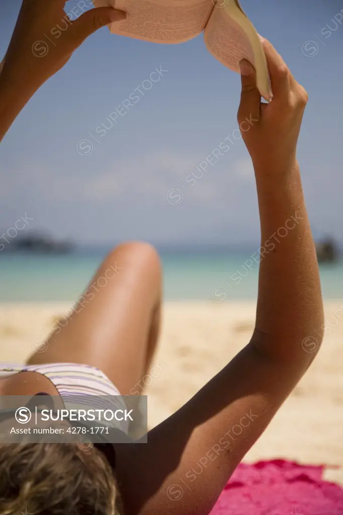 Close up of young woman reading book on beach