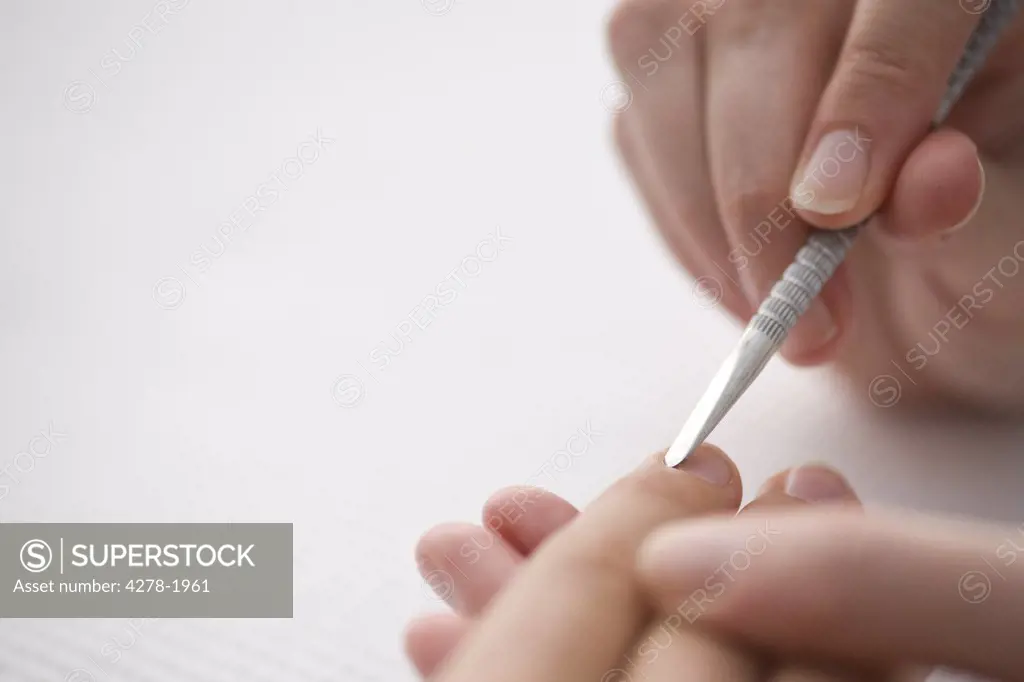 Close up of manicurist's hand pushing woman's cuticles with cuticle pusher