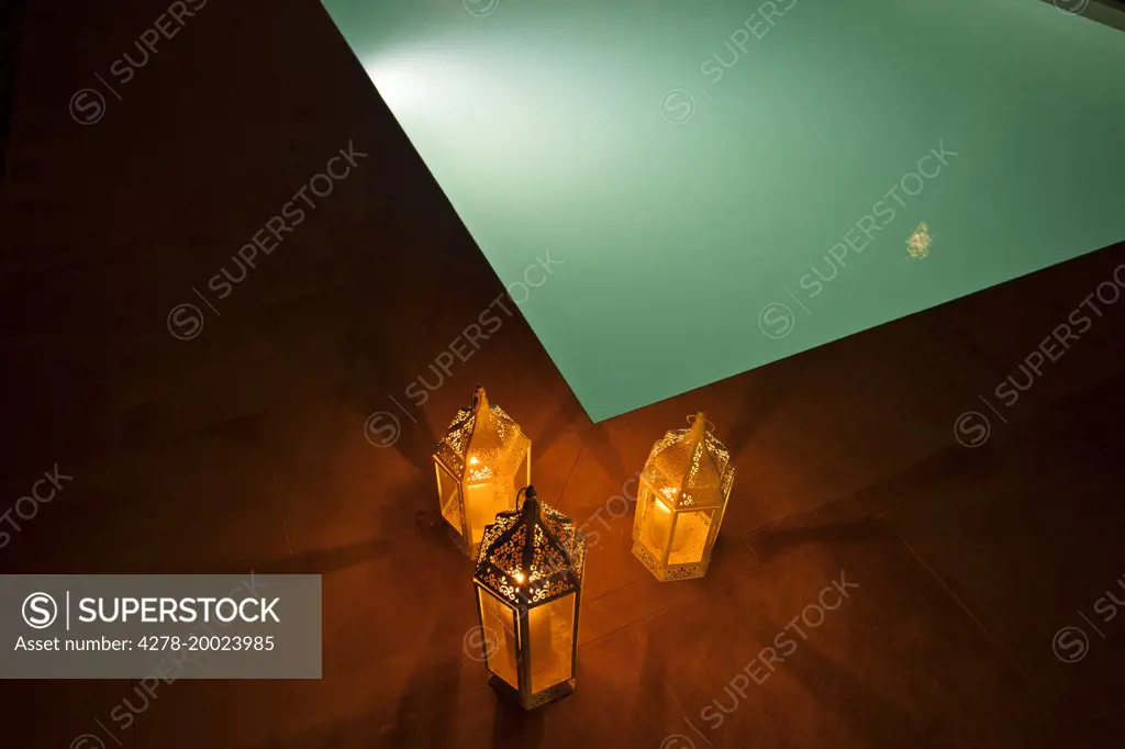 Candles Burning in Lanterns by Illuminated Swimming Pool, Close-up View