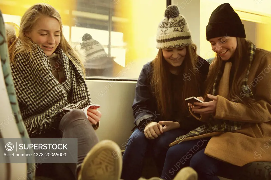 Teenage Girls Sitting on Train Using Smart Phone