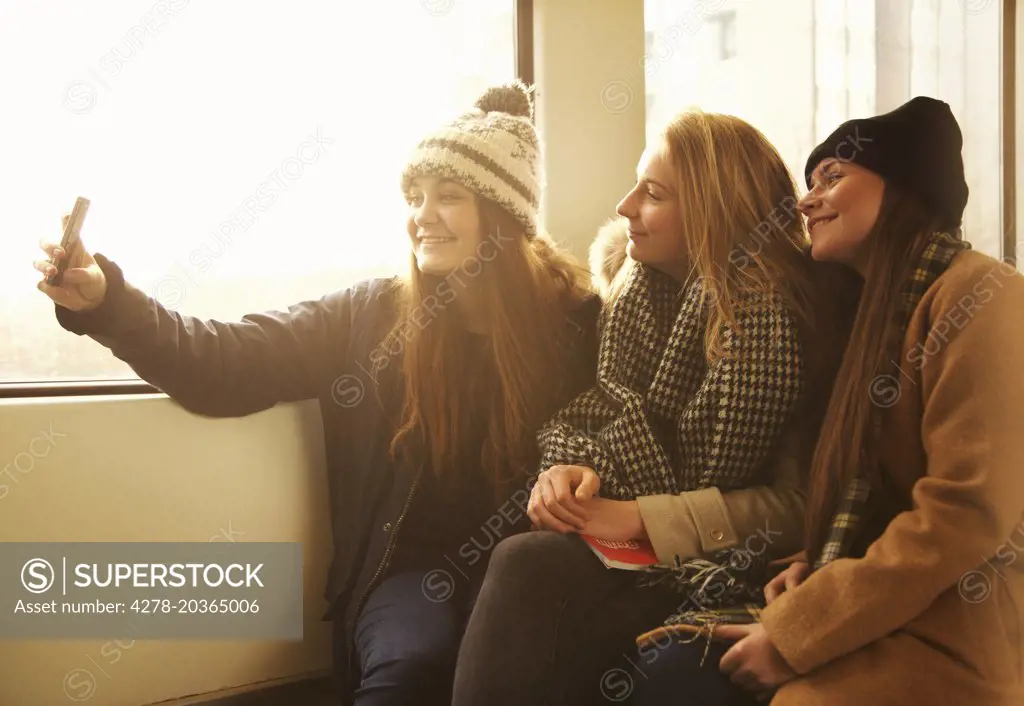 Teenage Girls Sitting on Train Taking Selfie