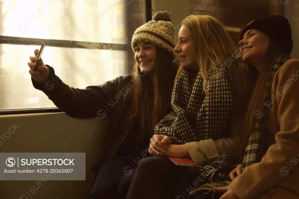 Teenage Girls Sitting on Train Taking Selfie