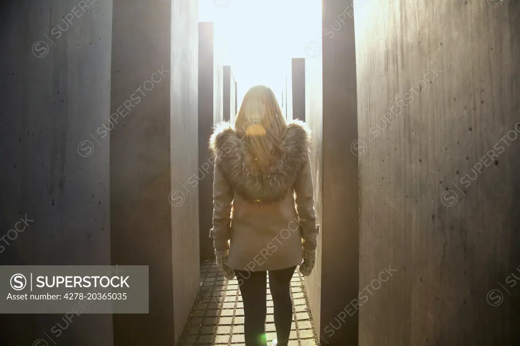 Back View of Young Woman Walking along the Concrete Steles of the Holocaust Memorial, Berlin, Germany