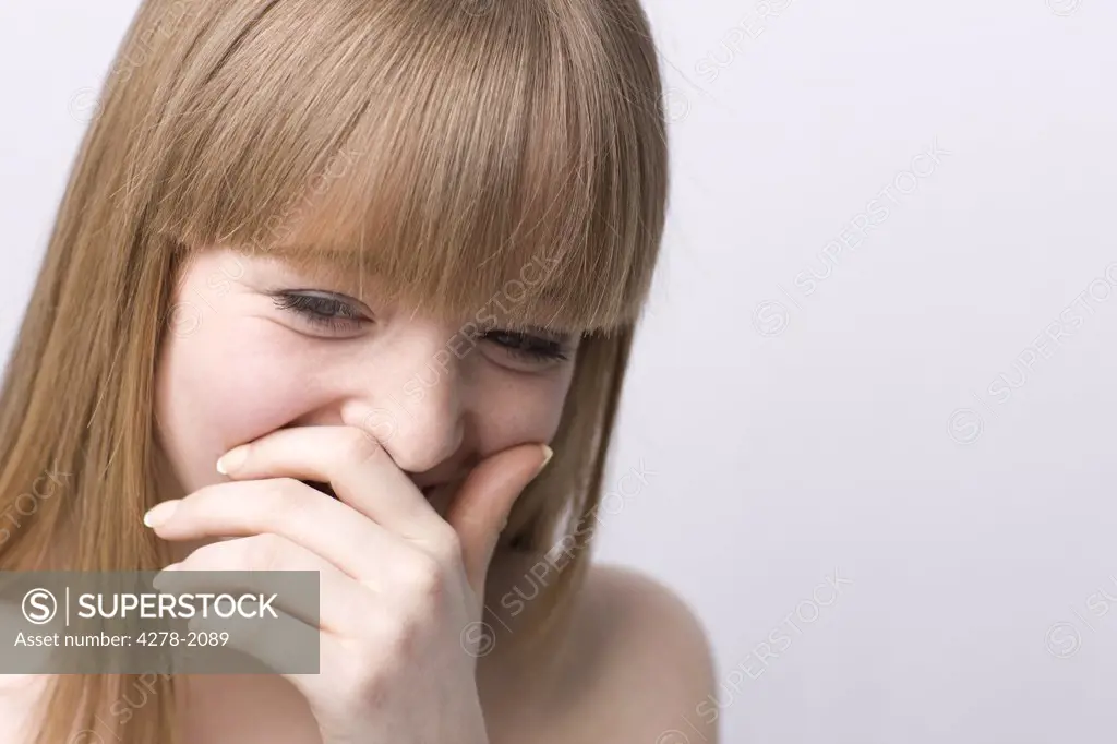 Young woman laughing with hand in front of mouth