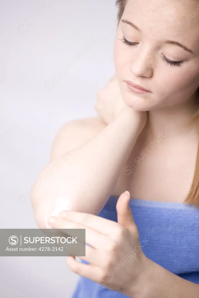 Woman applying body lotion on elbow