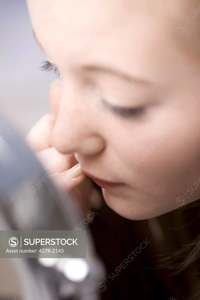 Close up of young woman applying lipstick with finger looking into the mirror