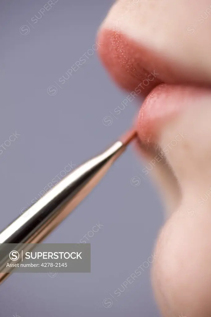 Close up of young woman lips with lipstick brush