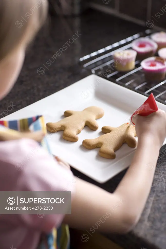 Back view of young girl decorating ginger bread man