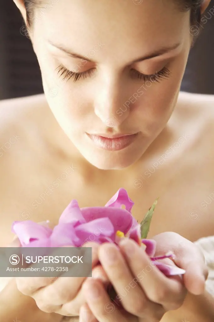 Portrait of a woman  inhaling fragrant bright pink petals in her hands