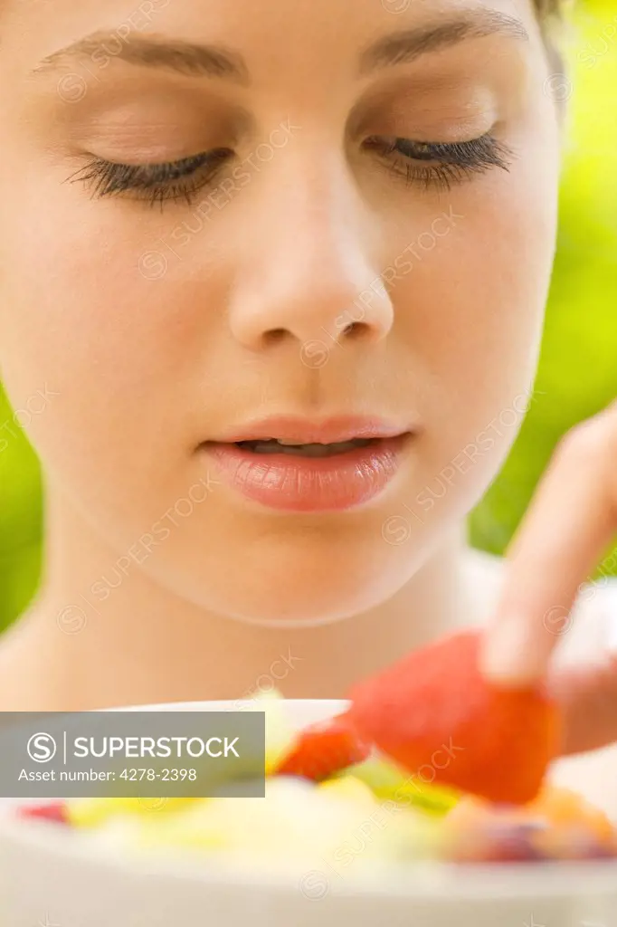 Close up of a young woman holding a strawberry