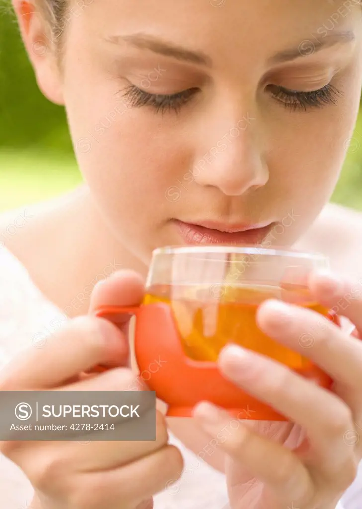 Close up of a young woman holding a cup of lemon tea