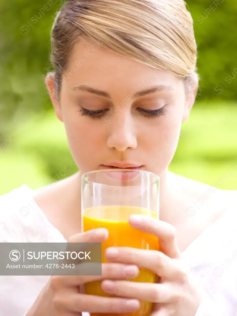 Close up of a young woman holding a glass of orange juice