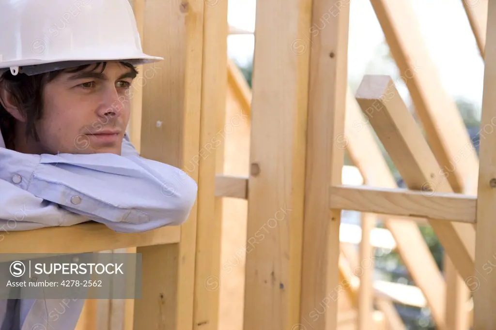 Portrait of a man leaning against beam in construction site