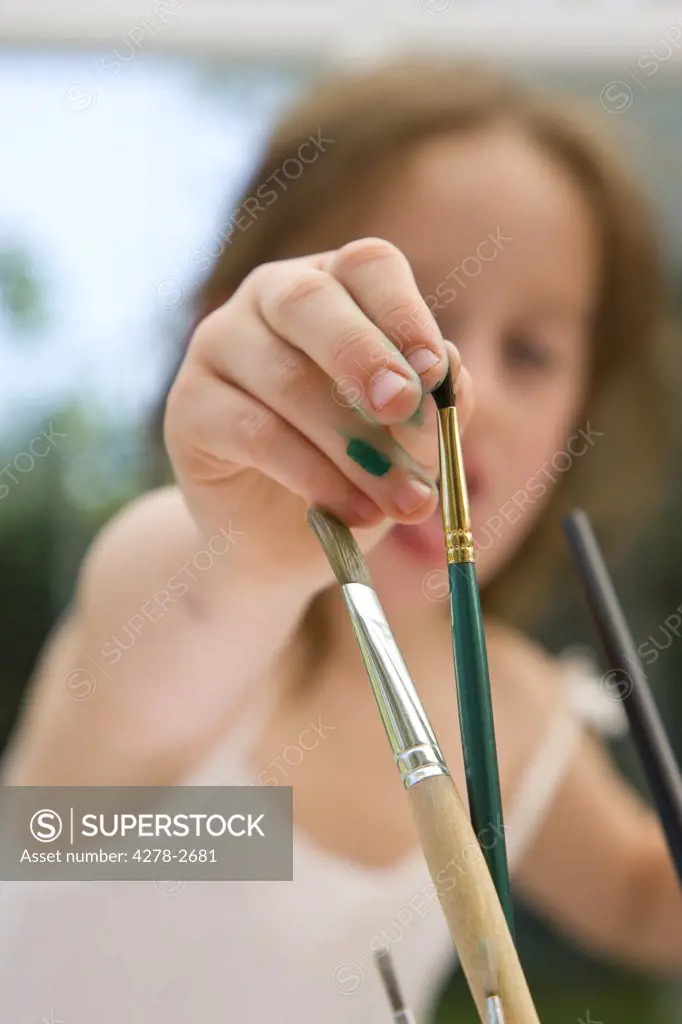 Young girl hand selecting a paintbrush