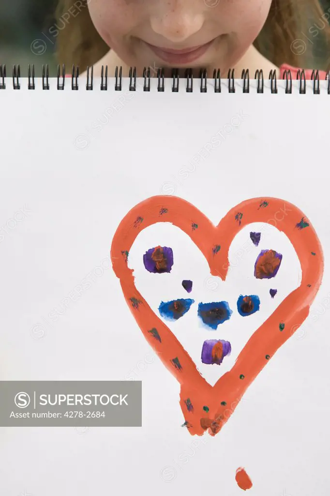 Young girl holding art book with heart on