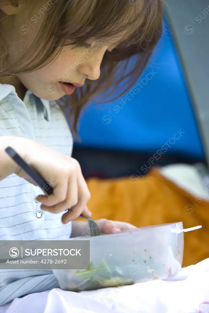 Close up of girl by tent entrance eating
