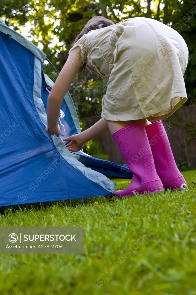 Back of young girl bending over fixing tent