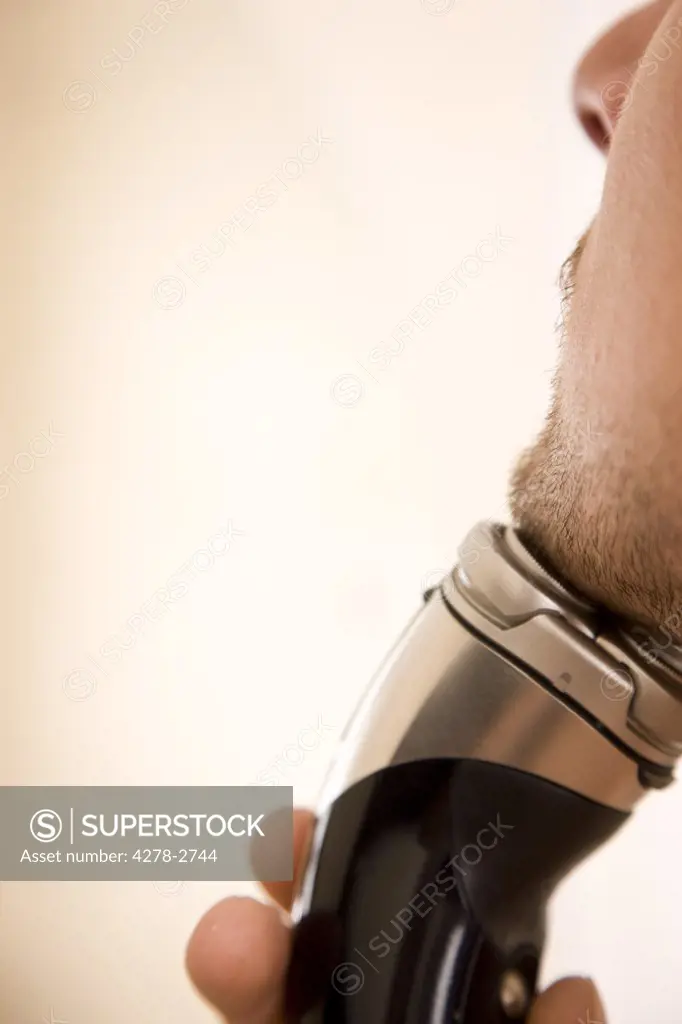 Close up of young man chin and electric razor