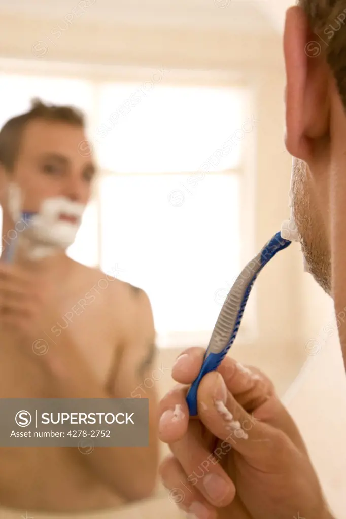 Close up of the back of a man head holding razor with mirror reflection